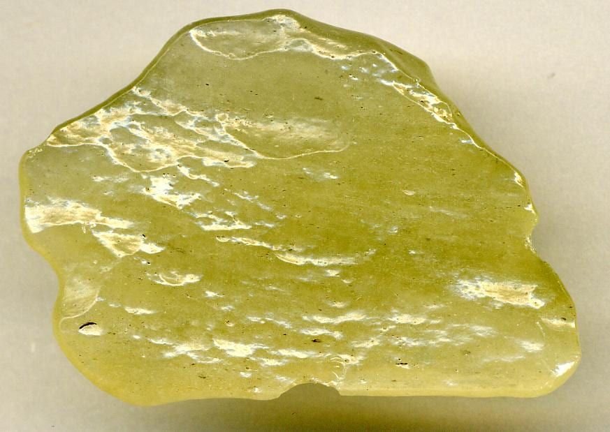 Rüzgârın taşıdığı kumla aşınmış yüzeyli yeşilimsi sarı bir parça (yaklaşık 4 cm)