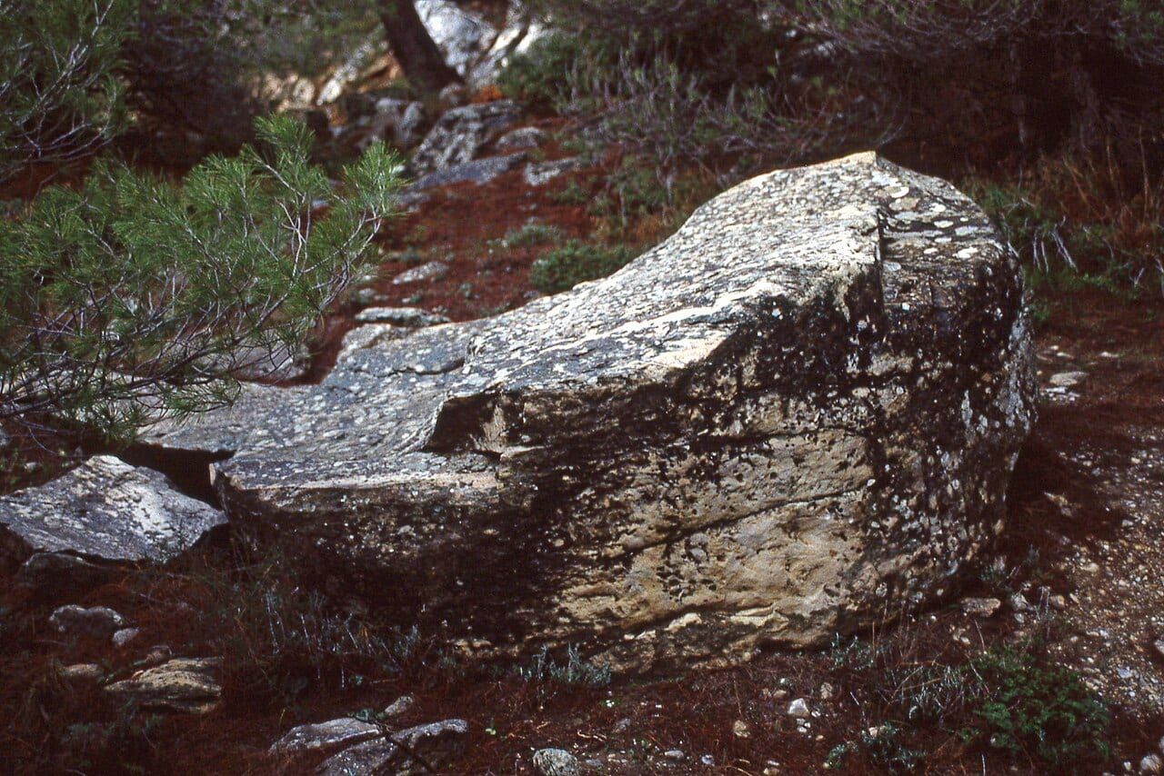 An abandoned column drum beside the drag path in the ancient Spilia quarry on Mount Pentelicus